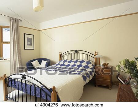 Blue White Quilt On Metal Bed In Cream Bedroom Stock