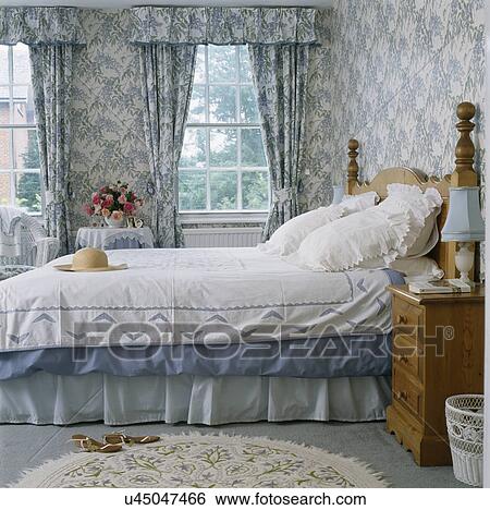 Stock Photograph - Blue+white wallpaper and matching curtains in traditional country bedroom . Fotosearch