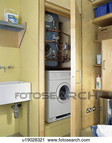 Boiler above washing-machine concealed in fitted cupboard in utility room View Large Photo Image Stock Image - Boiler above washing-machine concealed in fitted cupboard in utility room. Fotosearch