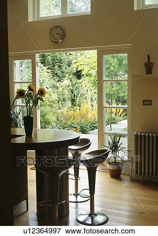 Bomba stools at breakfast bar in large modern kitchen with open doors to garden View Large Photo Image Stock Photo - Bomba stools at breakfast bar in large modern kitchen with open doors to garden. Fotosearch