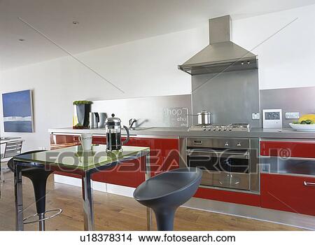 Bomba stools at metal table in large white kitchen with red fitted units View Large Photo Image Picture - Bomba stools at metal table in large white kitchen with red fitted units. Fotosearch