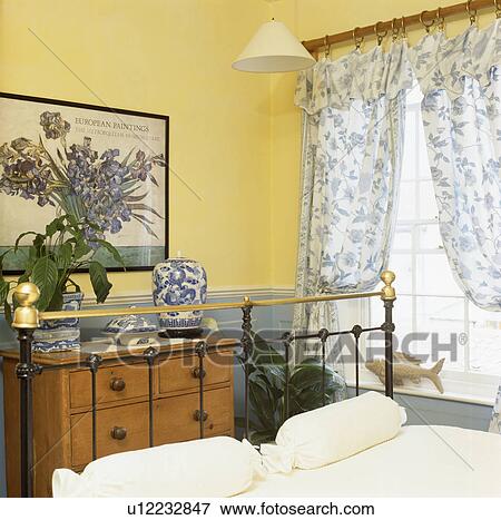 Brass bed and pine chest-of-drawers in yellow bedroom View Large Photo Image Stock Photo - Brass bed and pine chest-of-drawers in yellow bedroom. Fotosearch