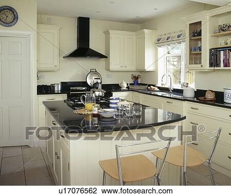 Breakfast set on island worktop with black granite unit in white country kitchen View Large Photo Image Stock Image - Breakfast set on island worktop with black granite unit in white country kitchen. Fotosearch