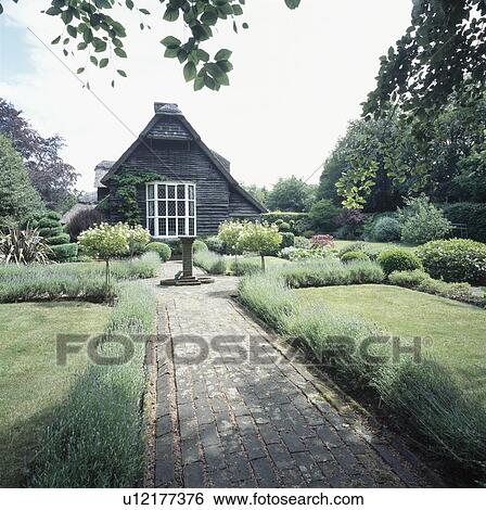 Brick Path Between Lawns Edged With Lavender In Country Cottage