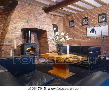 Brick walls and black leather sofas with modern wooden coffee table in living room with black stove in fireplace View Large Photo Image Stock Photography - Brick walls and black leather sofas with modern wooden coffee table in living room with black stove in fireplace. Fotosearch