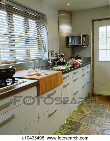 Built-in chopping block in fitted unit below window with slatted blind in modern kitchen View Large Photo Image Stock Photo - Built-in chopping block in fitted unit below window with slatted blind in modern kitchen. Fotosearch