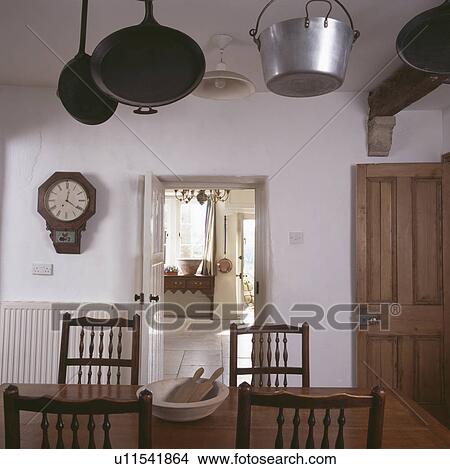 Cast-iron and steel pans on ceiling in simple white dining room View Large Photo Image Picture - Cast-iron and steel pans on ceiling in simple white dining room. Fotosearch