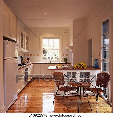Chairs and small table in modern white kitchen with wooden flooring View Large Photo Image Stock Photo - Chairs and small table in modern white kitchen with wooden flooring. Fotosearch