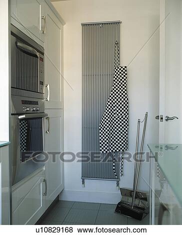 Checked apron on vertical stainless steel radiator in modern white kitchen View Large Photo Image Stock Photo - Checked apron on vertical stainless steel radiator in modern white kitchen. Fotosearch