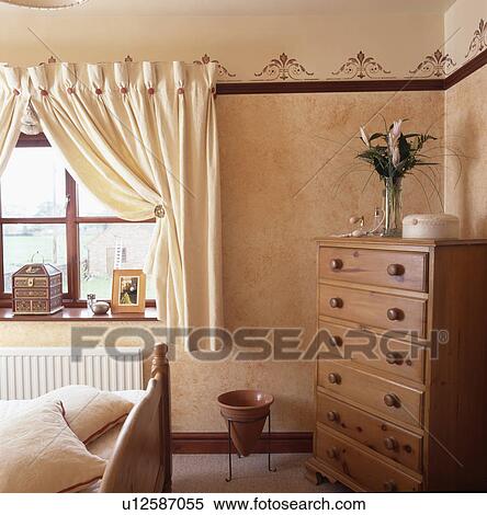 Chest-of-drawers in corner of small bedroom with cream curtains at window View Large Photo Image Stock Photography - Chest-of-drawers in corner of small bedroom with cream curtains at window. Fotosearch