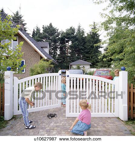 Children playing with remote-control toy car beside white garden gates View Large Photo Image Stock Photo - Children playing with remote-control toy car beside white garden gates. Fotosearch
