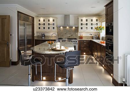 Chrome and black stools at island unit in modern kitchen with lighting in kickplates and white ceramic tiled flo View Large Photo Image Stock Image - Chrome and black stools at island unit in modern kitchen with lighting in kickplates and white ceramic tiled flo. Fotosearch