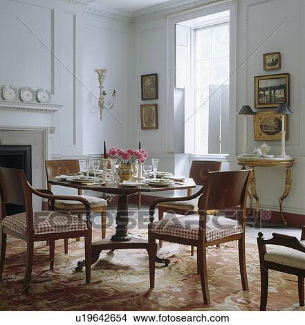 Picture - Circular antique table and chairs in traditional white townhouse dining room with antique silk carpet. Fotosearch
