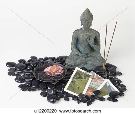 Cl0se-up of small statue of Buddha with joss sticks and black pebbles View Large Photo Image Stock Image - Cl0se-up of small statue of Buddha with joss sticks and black pebbles. Fotosearch