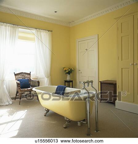 Clawfoot bath in the centre of yellow bathroom with white voile curtains View Large Photo Image Stock Image - Clawfoot bath in the centre of yellow bathroom with white voile curtains. Fotosearch