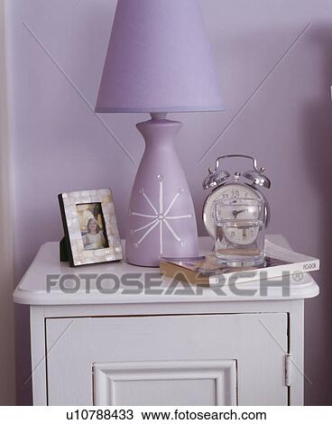 Close-up of alarm clock and mauve lamp on white bedside table View Large Photo Image Stock Image - Close-up of alarm clock and mauve lamp on white bedside table. Fotosearch