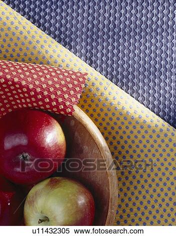 Stock Photography - Close-up of basket of apples on red, yellow and blue velour fabric swatches. Fotosearch