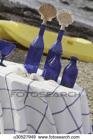 Close-up of blue bottles with seashell stoppers on table with checked cloth on beach View Large Photo Image Stock Photo - Close-up of blue bottles with seashell stoppers on table with checked cloth on beach. Fotosearch