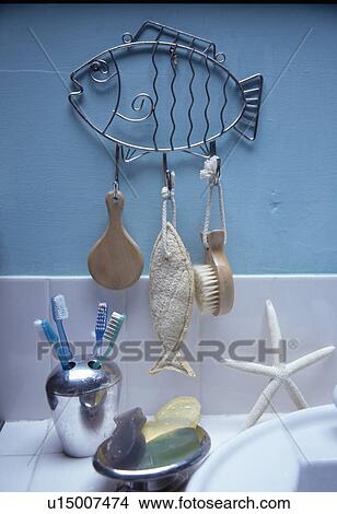 Close-up of brushes hanging from metal fish on bathroom wall above jar of toothbrushes View Large Photo Image Picture - Close-up of brushes hanging from metal fish on bathroom wall above jar of toothbrushes. Fotosearch