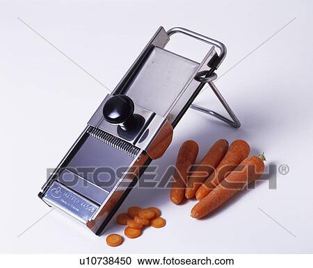 Stock Image - Close-up of carrots with stainless-steel vegetable slicer. Fotosearch