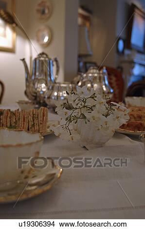 Close-up of china cups on table with small flower arrangement and silver tea set in the background View Large Photo Image Picture - Close-up of china cups on table with small flower arrangement and silver tea set in the background. Fotosearch