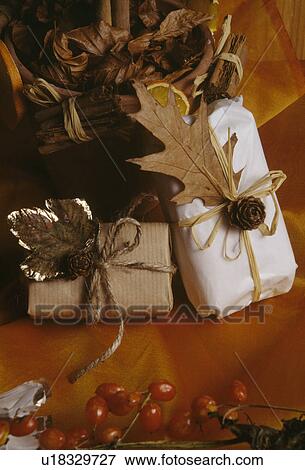 Stock Photo - Close-up of Christmas gifts wrapped in white paper and decorated with dried leaves and spices. Fotosearch