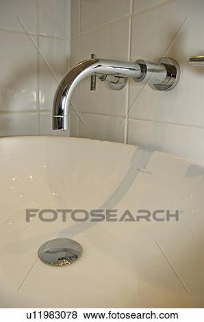 Stock Photo - Close-up of chrome tap and cream basin. Fotosearch