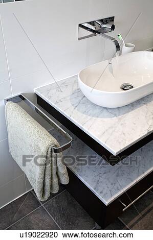 Close-up of chrome tap and shallow bowl-style basin on marble-topped vanity unit with towel storage View Large Photo Image Stock Image - Close-up of chrome tap and shallow bowl-style basin on marble-topped vanity unit with towel storage. Fotosearch