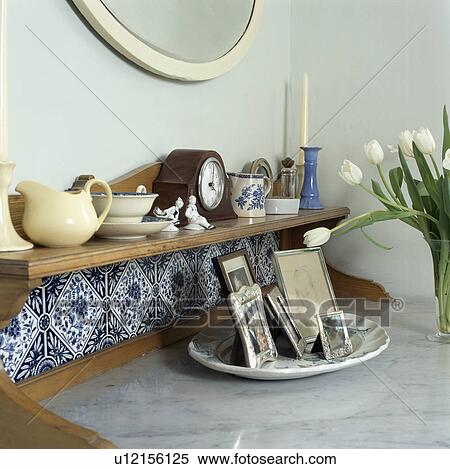 Stock Photography - Close-up of crockery and clock on shelf above marble-topped table. Fotosearch