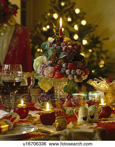 Close-up of crystallised fruit decoration on stemmed glass dish on table with lighted candles View Large Photo Image Stock Photograph - Close-up of crystallised fruit decoration on stemmed glass dish on table with lighted candles . Fotosearch