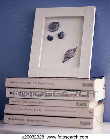 Stock Photo - Close-up of framed seashells on pile of paperback books. Fotosearch