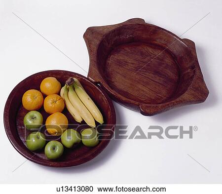 Stock Image - Close-up of fruit on wooden bowl beside wooden platter. Fotosearch