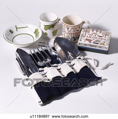 Stock Photo - Close-up of garden hand-tools in canvas holder beside pottery bowl and cups. Fotosearch