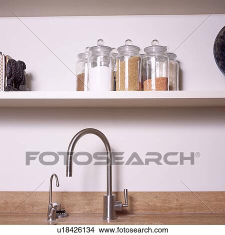 Close-up of glass storage jars on shelf above stainless steel taps View Large Photo Image Picture - Close-up of glass storage jars on shelf above stainless steel taps. Fotosearch