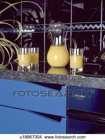 Close-up of glasses and glass jug of orange juice on kitchen worktop View Large Photo Image Picture - Close-up of glasses and glass jug of orange juice on kitchen worktop. Fotosearch