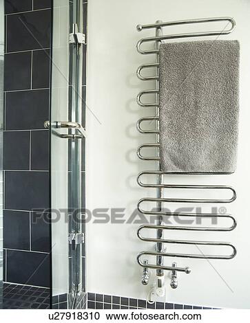 Stock Image - Close-up of grey towel on heated stainless steel towel rail. Fotosearch