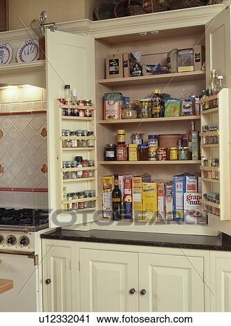 Stock Image - Close-up of groceries in fitted larder cupboard with open doors. Fotosearch