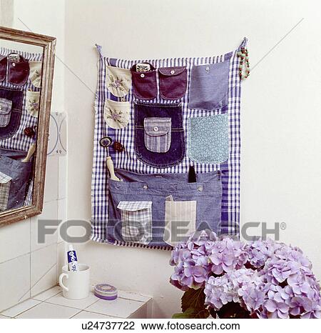 Stock Image - Close-up of hand-made fabric wall-hanging with pockets sewn-on and used as bathroom storage. Fotosearch