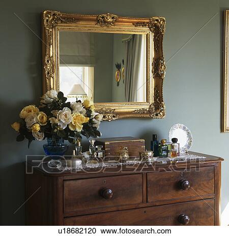 Close Up Of Large Gilt Mirror Above Chest Of Drawers In Blue