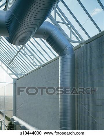 Stock Image - Close-up of large metal ducting below glass roof. Fotosearch
