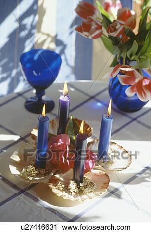 close-up of lighted blue candels in seashells on table with pink lilies in blue glass jug beside blue stemmed glass View Large Photo Image Stock Image - close-up of lighted blue candels in seashells on table with pink lilies in blue glass jug beside blue stemmed glass. Fotosearch