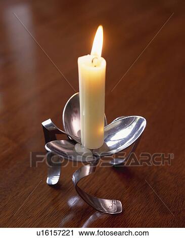 Stock Image - Close-up of lighted candle in modern stainless-steel candlestick. Fotosearch