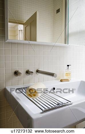 Close-up of loofah and steel rack on modern white basin below mirrored cabinet View Large Photo Image Stock Image - Close-up of loofah and steel rack on modern white basin below mirrored cabinet. Fotosearch