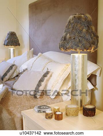 Close-up of metallic lamp with feather lampshade table beside bed piled with feather-trimmed cushions View Large Photo Image Stock Image - Close-up of metallic lamp with feather lampshade table beside bed piled with feather-trimmed cushions. Fotosearch
