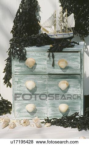 Stock Photo - Close-up of model ship on distressed painted chest-of-drawers with seashell handles. Fotosearch