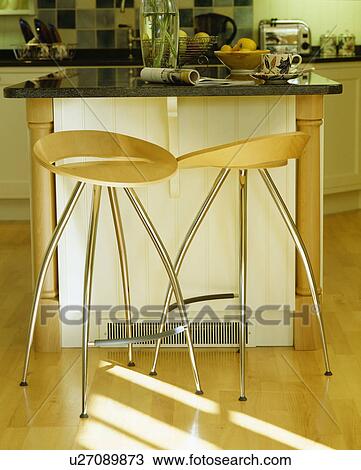 Stock Image - Close-up of modern pale wood and chrome stools. Fotosearch