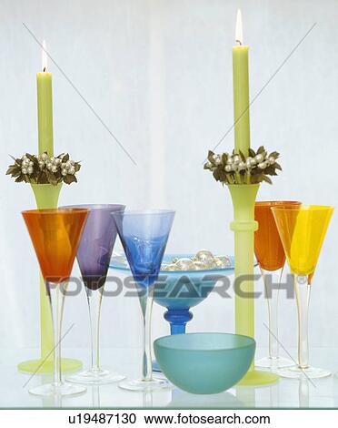 Stock Image - Close-up of multi-coloured wine-glasses with green candles in green glass candlesticks. Fotosearch