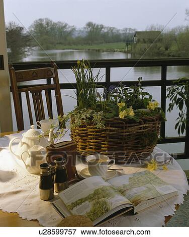 Close-up of open book and basket planted with spring flowers on table on balcony over-looking river View Large Photo Image Stock Photo - Close-up of open book and basket planted with spring flowers on table on balcony over-looking river. Fotosearch