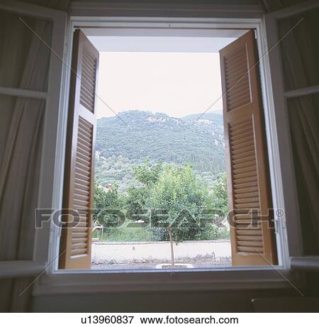 Stock Photo - Close-up of open window and shutters with view of mountains on Kefalonia. Fotosearch