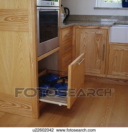 Close-up of openpan drawer below oven in pale wood kitchen View Large Photo Image Stock Image - Close-up of openpan drawer below oven in pale wood kitchen. Fotosearch